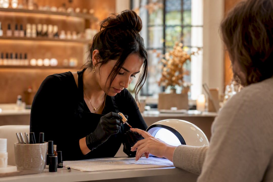 Technician curing gel nails with UV lamp