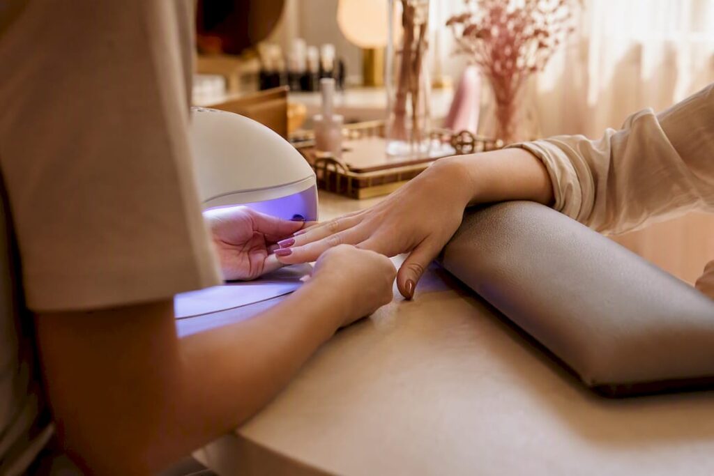 Hands curing nails under UV lamp