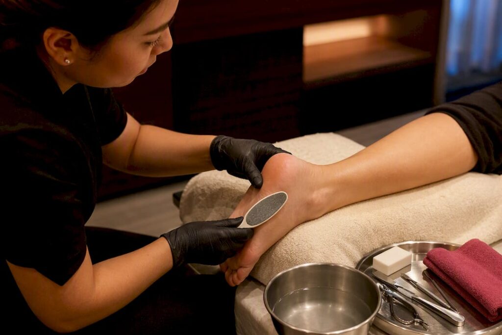 Technician smoothing heel during spa pedicure