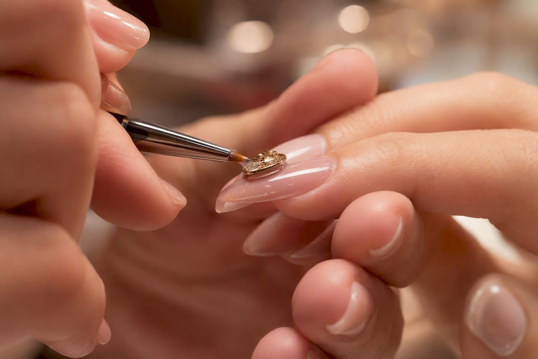 Technician sealing builder gel beneath nail charm