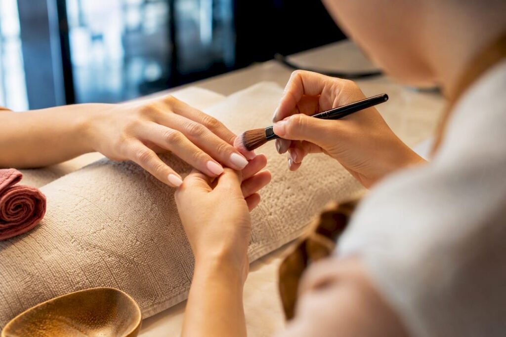 Technician applying dip powder to natural nails