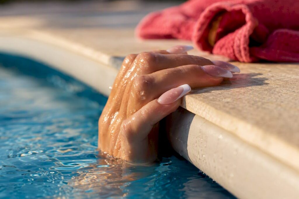 Acrylic nails gripping a pool edge