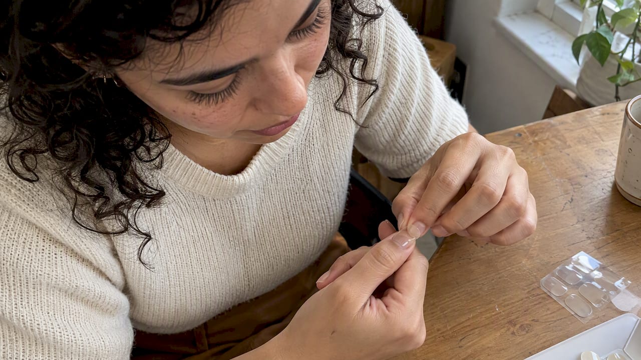 Hand applying a clear nail sticker