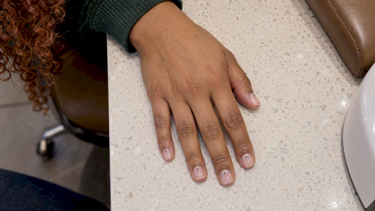 Small neutral nail-art dots near cuticles